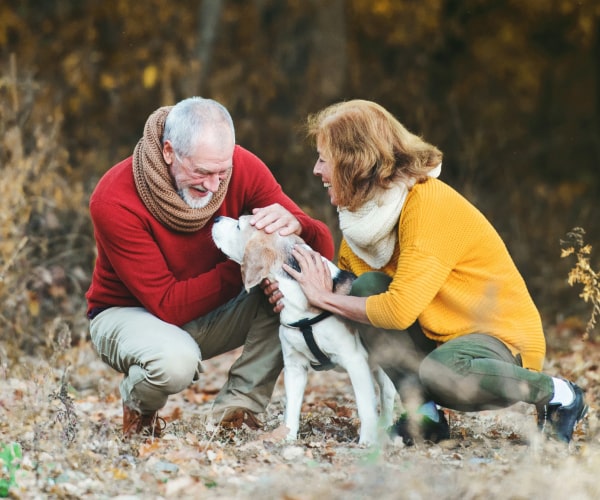 Two persons with their pet dog loving him